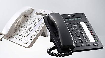 White Panasonic KX-T7730 telephone with keypad and display screen, showing a classic office phone design.