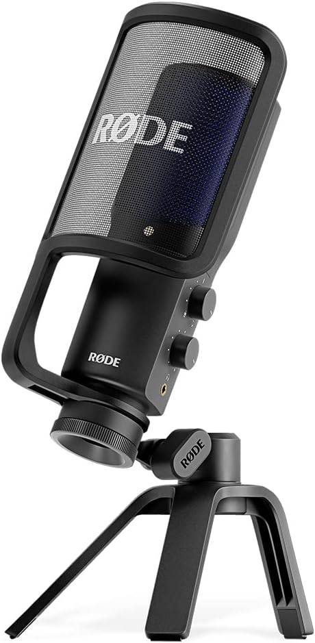 Black Rode NT-USB+ condenser microphone for USB recording, shown on a desk with professional audio equipment.