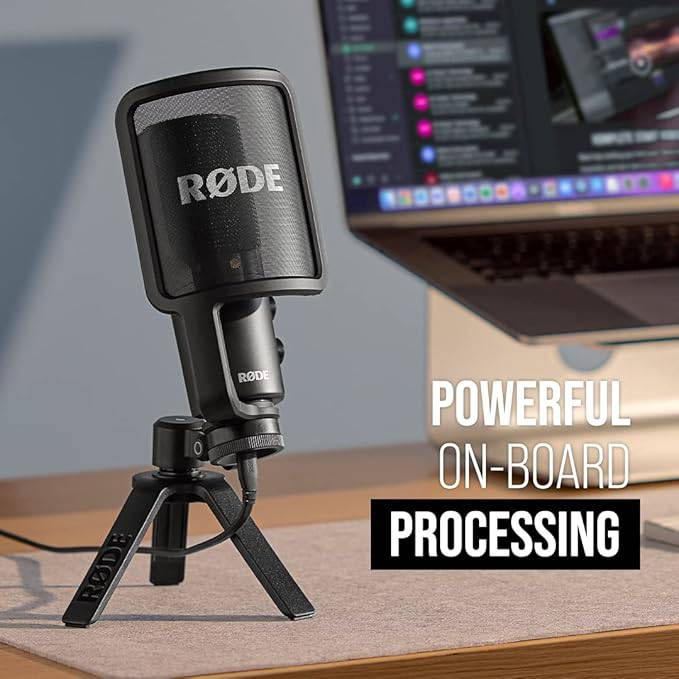 Black Rode NT-USB+ condenser microphone for USB recording, shown on a desk with professional audio equipment.